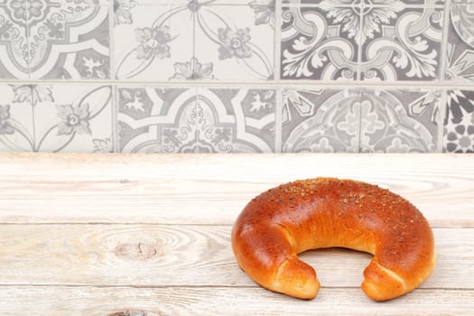 Delicious circular bread sitting on a rustic wooden surface with decorative tiles in the background.