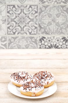 Three delightful donuts, generously topped with colorful icing and festive sprinkles, beautifully arranged on a plate