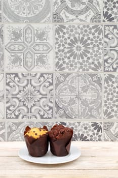 Two visually appealing muffins are placed on a decorative tile backdrop, showcasing food and interior design
