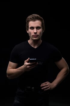 Handsome man in black tshirt with a phone in his hand waist up portrait