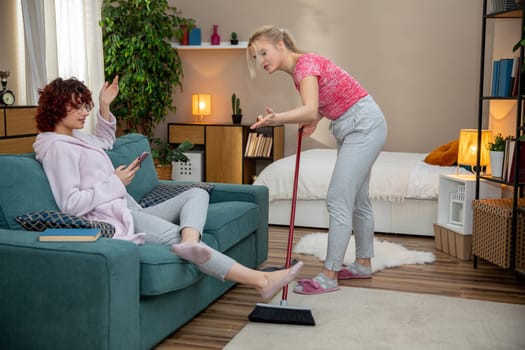 Two friends happily clean a cozy living room, showcasing their teamwork and commitment to home care