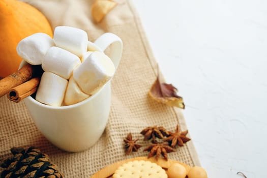 Warm autumn scene with hot chocolate, marshmallows, spices, leaves, and cozy sweater. Perfect for seasonal content.