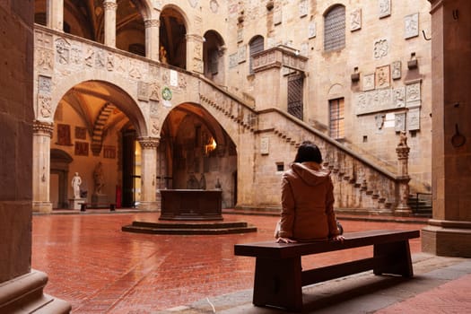 Florence, Italy, January 6, 2024: Woman sitting watching the amazing courtyard of the Bargello Museum