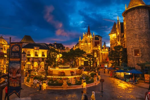 Square of the medieval city with the Catholic Cathedral in the French village in the Ba Na Hills tourist Park in the evening. Da Nang, Vietnam - September 13, 2024