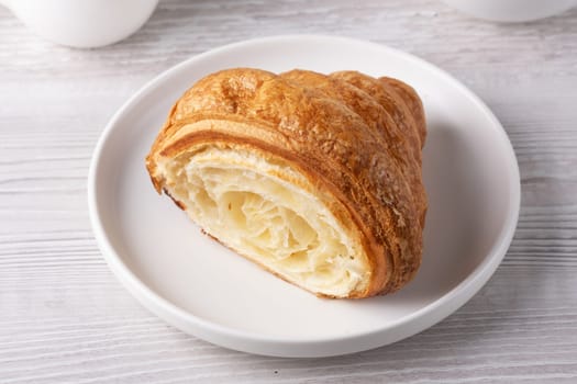 Freshly baked croissant served on a white plate.