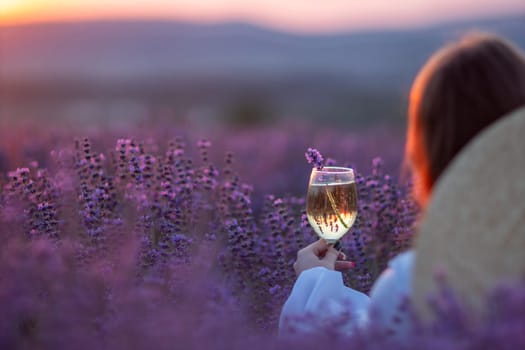 Here's a caption under 150 characters: Woman sits in lavender field at sunset, holding a glass of white wine. Peaceful, idyllic scene.