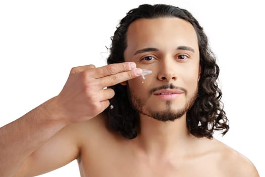 A young man demonstrates skincare routine with moisturizer on his face close up