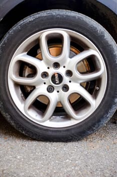Cremona, Itally - October 6th 2024 Close-up of a dirty silver alloy wheel and tire on a mini cooper s r56 parked on asphalt. Showcasing intricate details and contrasting colors