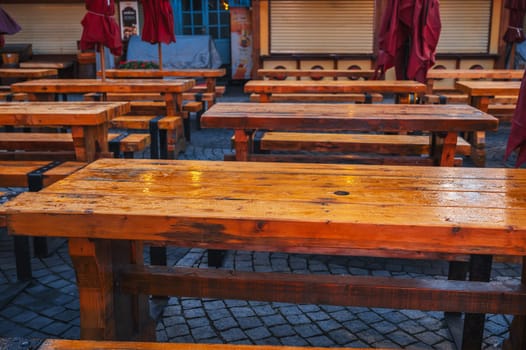 wooden tables and benches in a street cafe in the evening in the rain