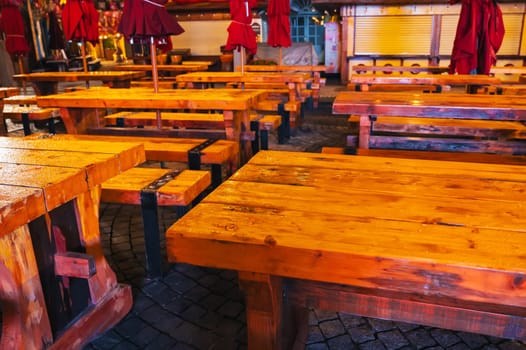 wooden tables and benches in a street cafe in Europe in evening