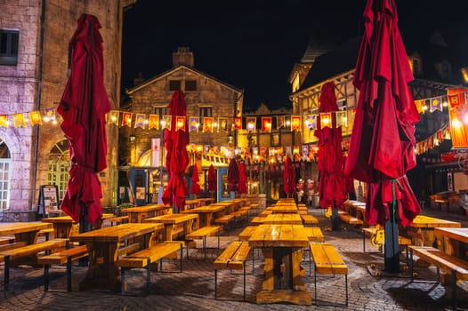 Decorated interior of the festive outdoor cafe restaurant with wooden tables and benches in the night in Ba Na Hills Park. Da Nang, Vietnam - September 13, 2024