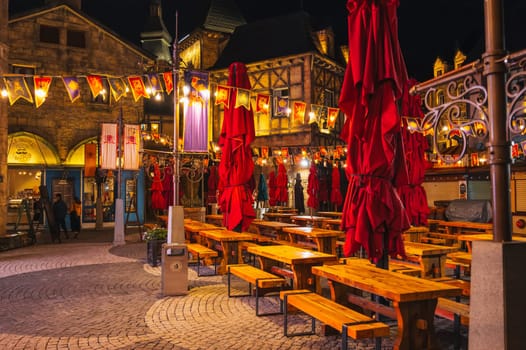 Interior of the festive street outdoor cafe restaurant with wooden tables and benches in night in Ba Na Hills Park. Da Nang, Vietnam - September 13, 2024