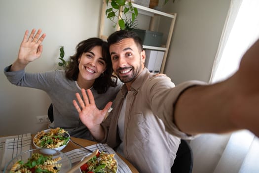 Selfie picture of happy couple having lunch together at home dining table looking at camera. Lifestyle concept.