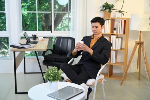 Professional businessman relaxing with a cup of coffee in modern office.