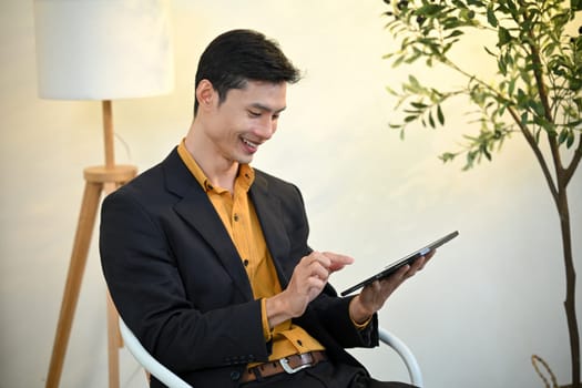 Smiling asian executive reviewing information on digital tablet in a bright office space.