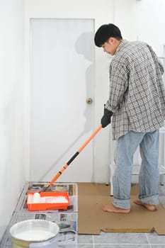 Man standing on protected surface covered with newspapers working on home renovation project.