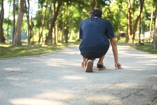 Back view of man in a starting position on the ground, ready to sprint. Goals and motivation concept.