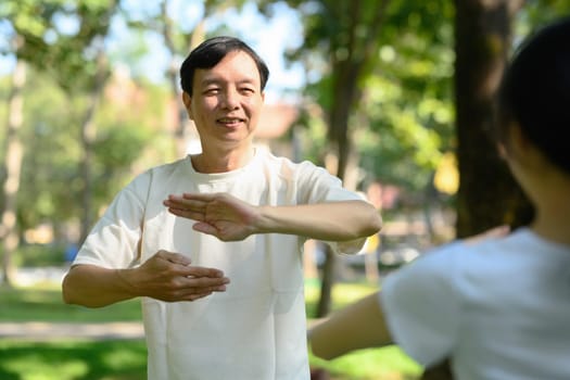 Smiling middle age man practicing Tai Chi in the morning. Mental health and well-being.concept.