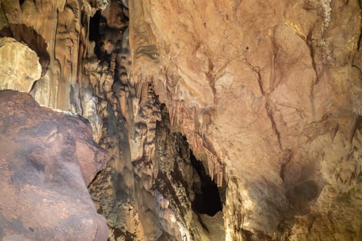 A cave with a brown ceiling and a brown floor. The cave is dark and has a mysterious atmosphere