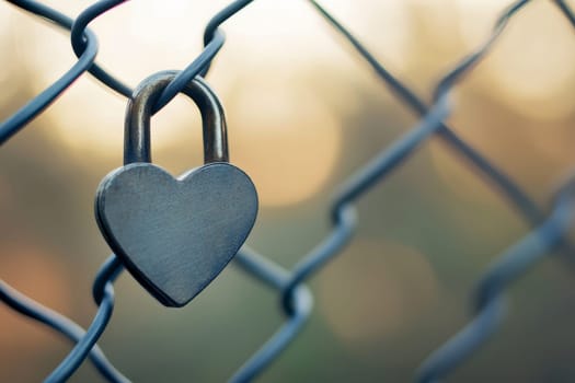 Valentine heart padlock attached to wire mesh fence..