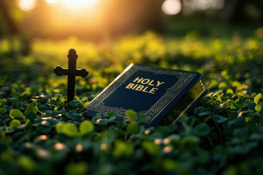 a bible book and a cross lying on the green clover leaves..
