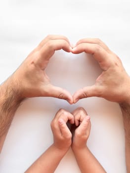 Adult and child hands forming heart shape on white background.