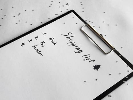 Holiday shopping list on festive clipboard with star confetti and seasonal decorations.