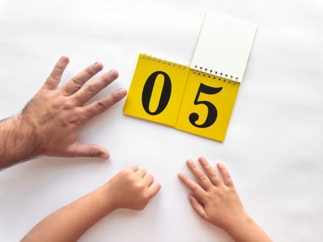 Adult and child hands counting with calendar showing number five on white background.