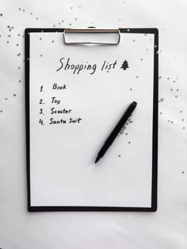 Festive shopping list on clipboard with glitter accent and black marker.