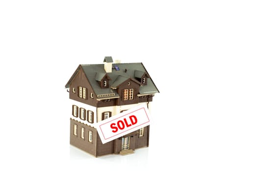 A detailed miniature house model with a prominent sold sign, symbolizing real estate success and property transactions. Ideal for concepts of home buying and real estate sales.