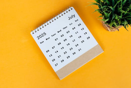 Jul 2025 desk calendar on yellow background. Directly above. Flat lay. Copy space.
