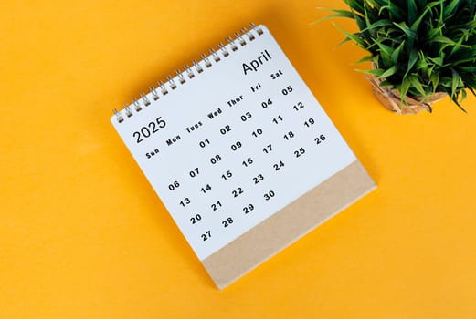 April 2025 desk calendar on yellow background. Directly above. Flat lay. Copy space.