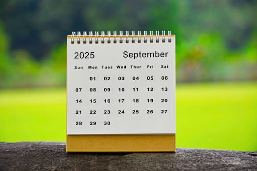 September 2025 white calendar with green blurred background.