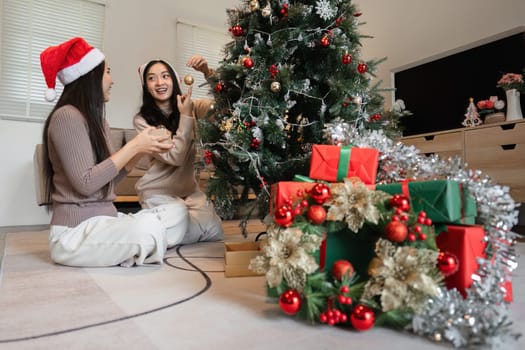 Young women joyfully celebrating Christmas at home, surrounded by festive decorations and a beautifully adorned tree.