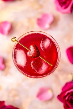 A charming Valentine's Day cocktail with bright red shades, decorated with a slice of strawberry in the shape of a heart.
