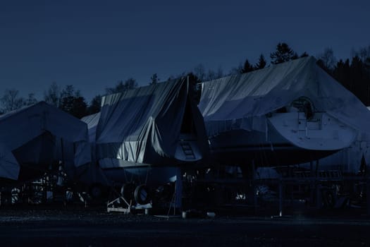 Sailboats are covered, protected and stored out of the water for the winter at night, winter storage for the sailboat in Finland, winterizing , short season in Northern country, cold conditions