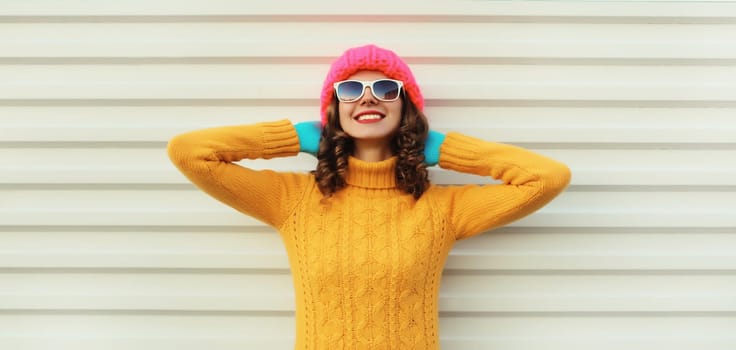 Winter christmas portrait of happy young woman smiling dreams relaxation in yellow sweater, pink hat on white background