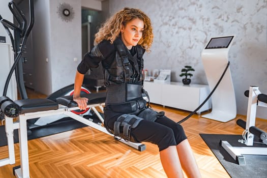 A woman in sleek workout attire performs a body toning exercise indoors.