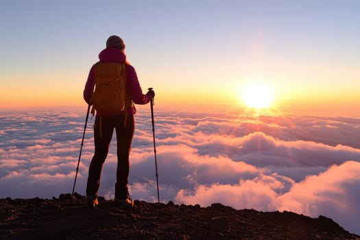A lone adventurer stands atop a mountain, gazing at a stunning sunrise above a sea of clouds. Ideal for nature lovers and adventurers.