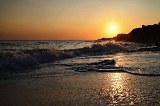 Beautiful sunset on the beach with the sea. Waves on the sea. Greece - Corfu island (Kerkyra) Agios Georgios. A concept for travel, holidays and summer vacations. 