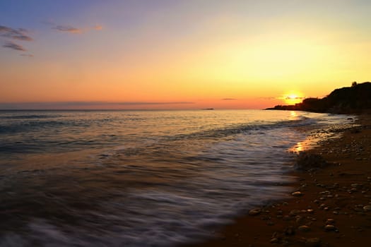 Beautiful sunset on the beach with the sea. Greece - island of Corfu (Kerkyra). Concept for travel, holidays and summer vacations. 