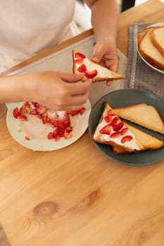 Top view, a woman making cream cheese toast with strawberries for a snack.