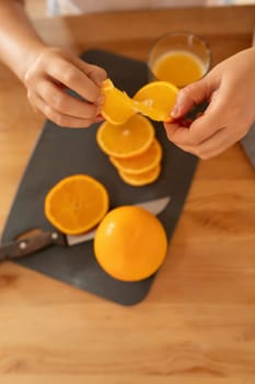 a woman's hands holding a juicy orange sitting in the kitchen.