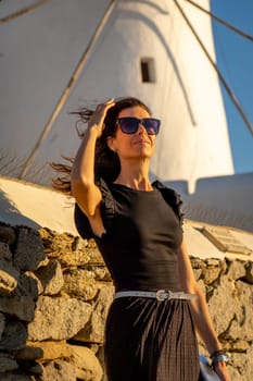 Young woman in black dress at the windmills in Mykonos