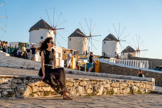 Young woman in black dress at the windmills in Mykonos