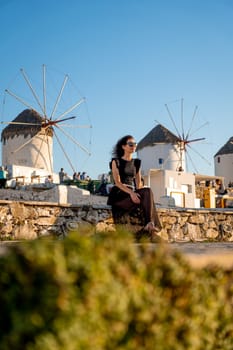 Young woman in black dress at the windmills in Mykonos