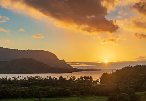 Sun slowly setting over the ocean of Hanalei Bay on the north coast of the Hawaiian island of Kauai