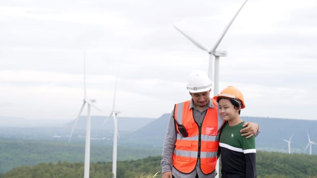 Engineer with his son on a wind farm atop a hill or mountain in the rural. Progressive ideal for the future production of renewable, sustainable energy. Energy generation from wind turbine.