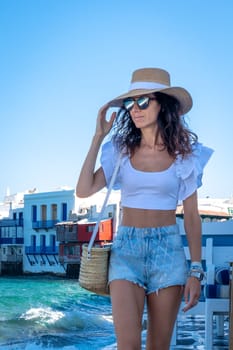 Young girl with jean shorts and hat walking in Little Venice, Mykonos