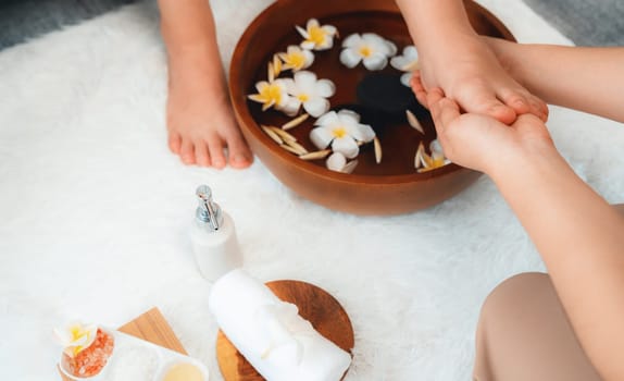 Woman indulges in blissful foot massage at luxurious spa salon while masseur give reflexology therapy in gentle day light ambiance resort or hotel foot spa. Quiescent